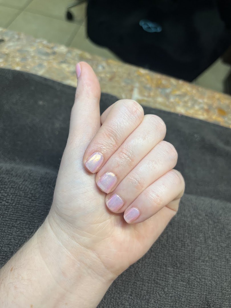 Nail technician shaping nails at a salon table.